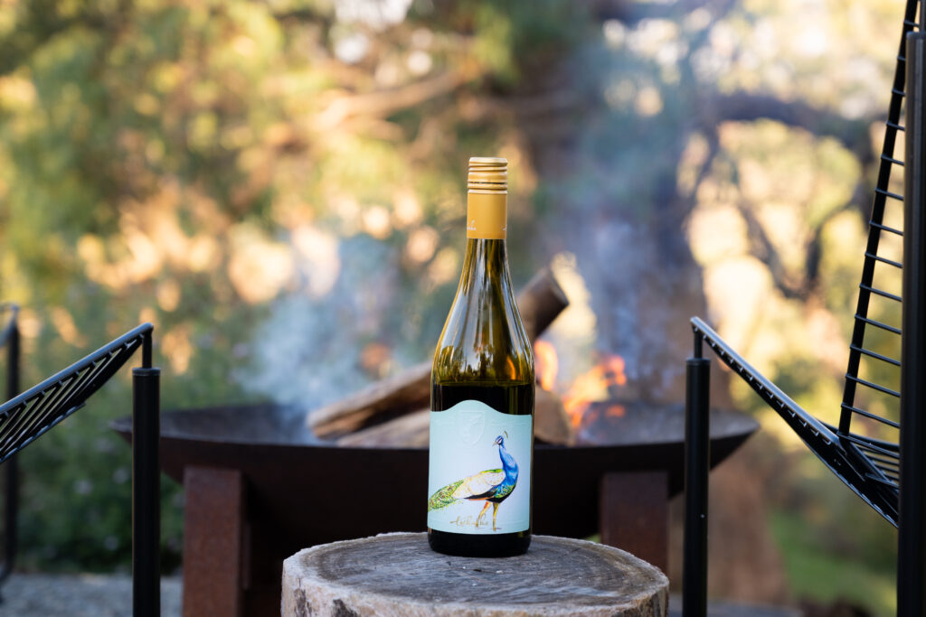 Bottle of Tscharke wine beside an outdoor fire pit at Kaiser Ridge eco stay